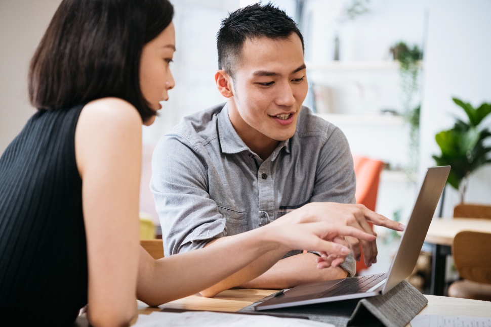 two people talking while pointing to a laptop screen