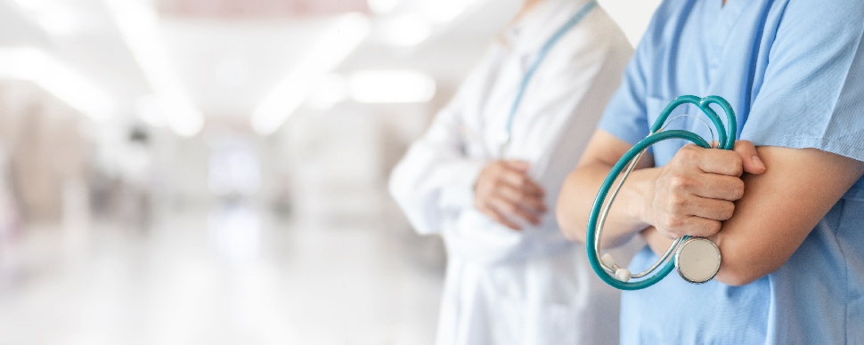 Two doctors standing with folding arms and one holding a stethoscope