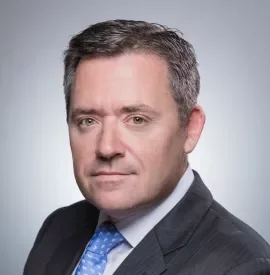 Portrait of a man in a suit with a light blue tie.
