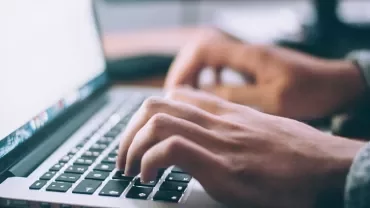 Close-up of hands typing on a laptop keyboard