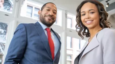 Two business professionals standing in a bright office environment.