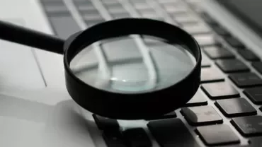 Magnifying glass on keyboard, close-up view.