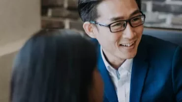 Man in blue suit smiling during a meeting.