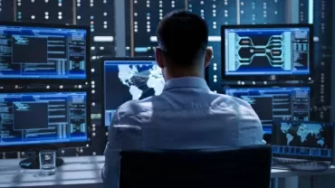 Person working in a tech hub with multiple monitors displaying data