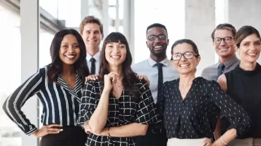 A diverse group of smiling professionals standing together in an office setting.