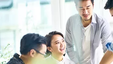 A group of four people collaborating in a bright office with plants.