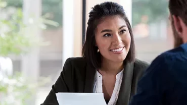 Woman smiling during a conversation with a man in an office setting.