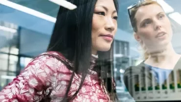 Two women looking at a computer screen in a modern office.