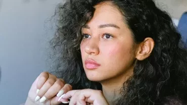 Person with curly hair attentively listening in a meeting.