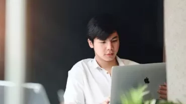 A man sitting at a laptop, discussing career growth opportunities for top talent in a professional setting.