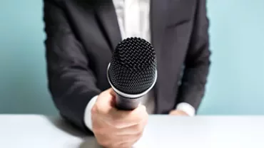 Close-up of a person in a suit holding a microphone.