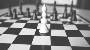 Close-up of a white pawn on a chessboard in black and white.
