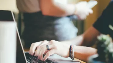 Person typing on a laptop in a casual setting.