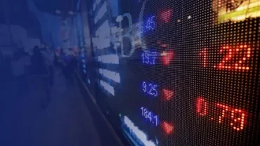 Close-up of a stock market display board showing numerical data and downward red arrows.