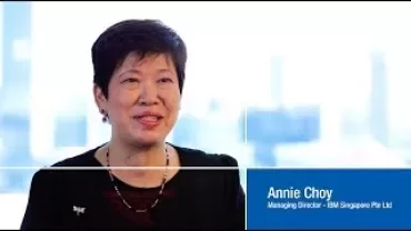Woman smiling in a professional setting with a cityscape background.