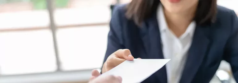 Person handing over a business card in an office setting.