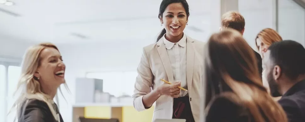 Business meeting with a woman leading a discussion, colleagues smiling and interacting.