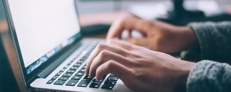 Close-up of hands typing on a laptop keyboard