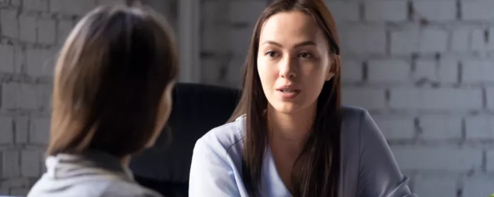 Two women having a conversation in an office.