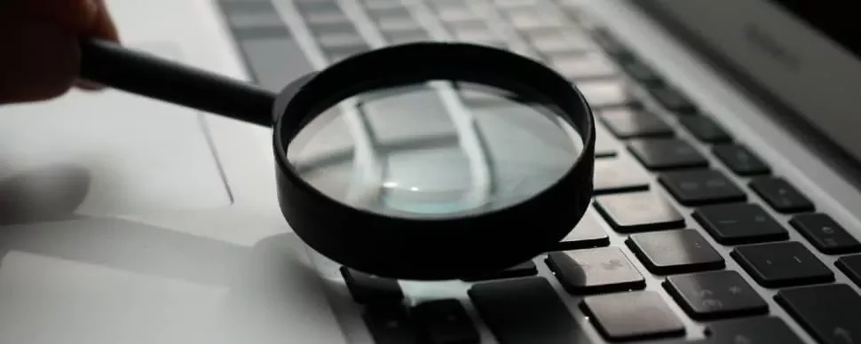 Magnifying glass on keyboard, close-up view.