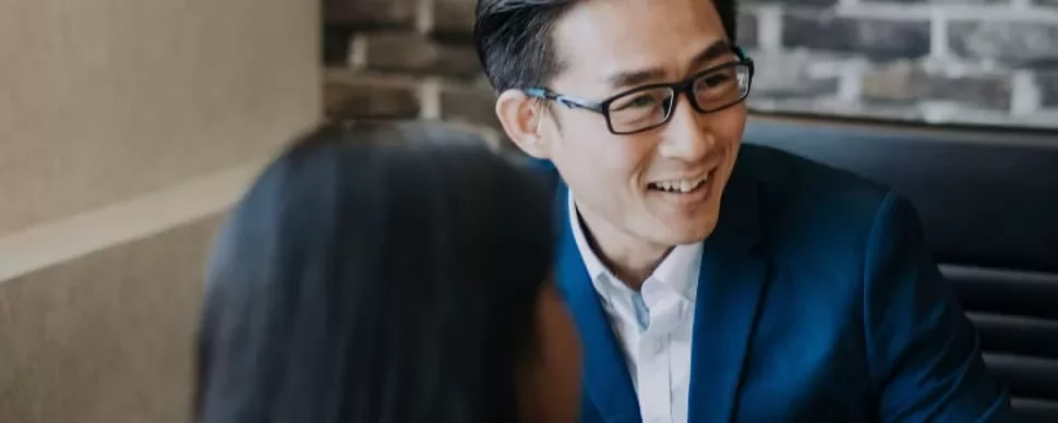 Man in blue suit smiling during a meeting.