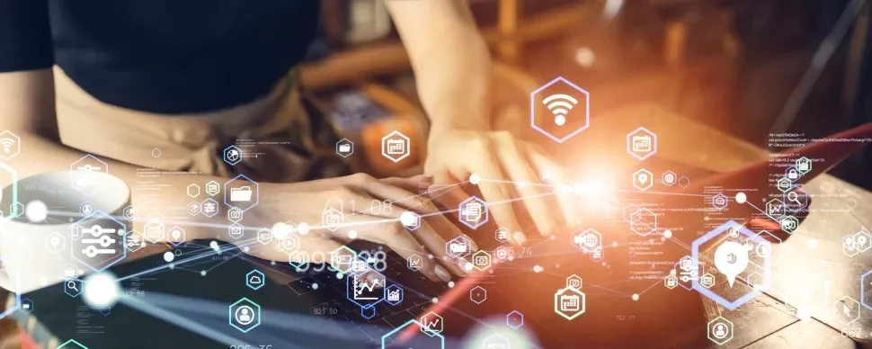 Person typing on a laptop surrounded by digital icons.
