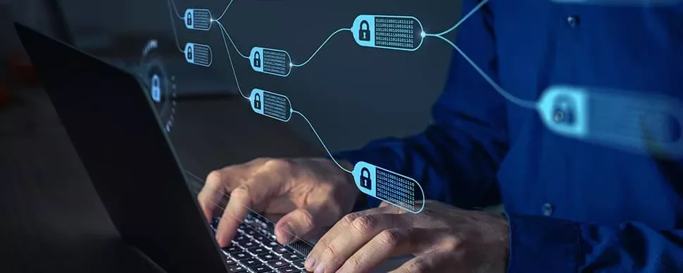 Person typing on laptop with digital blockchain graphics in the foreground.