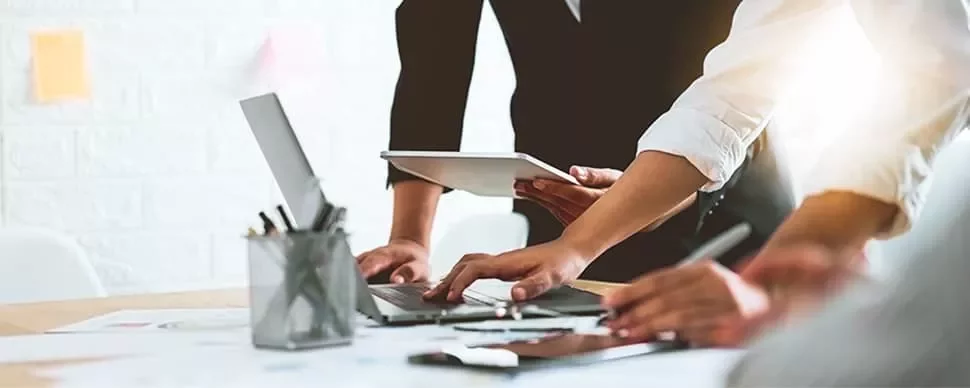 People collaborating around a table with laptops and tablets.