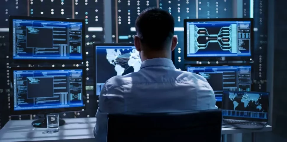 Person working in a tech hub with multiple monitors displaying data