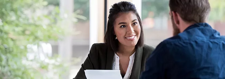 Woman smiling during a conversation with a man in an office setting.