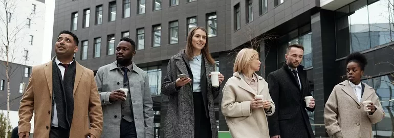 six people walking together in the business district, with a cup in hand