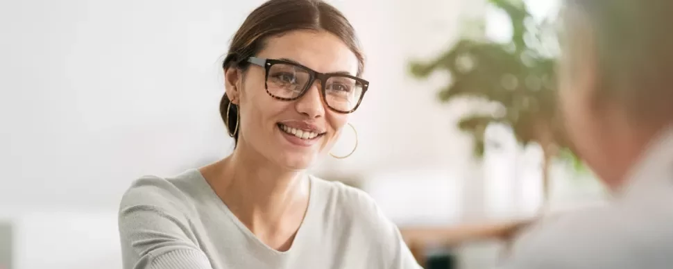 A female candidate wearing glasses smiling as she answers secretary job interview questions.