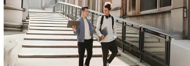 Two fresh graduates walking down the stairs while discussing job interview questions