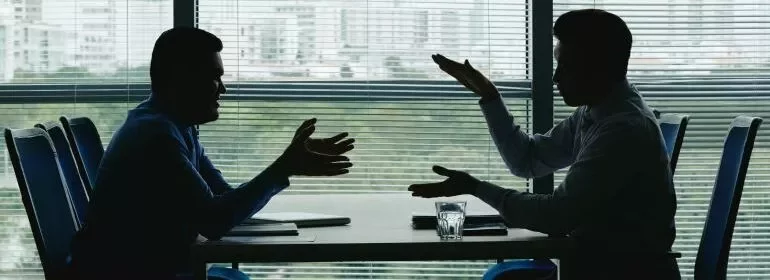 Silhouette of two business professionals engaged in conversation at a table, emphasising collaboration and discussion.