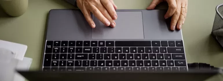 Individual engaged in typing on a laptop, with fingers on the keyboard.