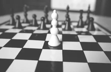 Close-up of a white pawn on a chessboard in black and white.